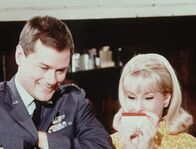 Bezaubernde Jeannie – Obwohl Jeannie (Barbara Eden, r.) und Tony (Larry Hagman, l.) Dr. Bellows vorgeschwindelt haben, auf eine Jagdpartie zu gehen, nehmen sie an Rogers Party teil.