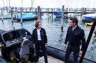 WaPo Bodensee – Julia Demmler (Wendy Güntensperger, l.) holt ihren Kollegen Jakob Frings (Max König, r.) für einen gefährlichen Einsatz ab. Sie sollen zwei Bankräuber stellen.