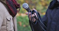 Campus Talks – Man talking to a journalist with micro outdoor. Unrecognizable. Bokeh