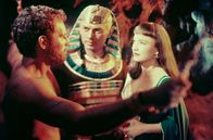Zehn Gebote – Nachdem er seine wahre Identität erfahren und seiner Berufung gefolgt ist, stehen Moses (Charlton Heston, l.), der neue Pharao Ramses (Yul Brynner) und dessen Frau Nefretiri (Anne Baxter) sich als Feinde gegenüber.