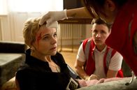 Die Notärztin – Nina (Sabrina Amali, r.) und Paul (Paul Zichner, M.) versorgen Frau Ahrens (Greta Galisch de Palma, l.), die sich in der Küche eine Platzwunde zugezogen hat.