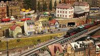 Eisenbahn-Romantik – Vorbei am Bahnhof Lommatzsch geht es unterhalb der Stadthäuser von Meißen zurück zum Lokschuppen. Vielfältige Szenen aus der Heimat der Arbeitsgemeinschaft Meißen umrahmen den einfahrenden Güterzug.