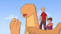 Tom – Dinosaurier Tom transportiert seine Freunde Tip und Wanda auf seiner linken Pfote.