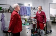 Sturm der Liebe – Erik (Sven Waasner, r.) tut sich schwer damit, dass Werner ihn zu Hilfsarbeiten in Andrés (Joachim Lätsch, l.) Küche verdonnert hat.