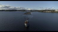 Wildes Skandinavien – Boot, das Baumstämme auf dem Fluss zieht.
