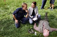 Die Rosenheim-Cops – Pathologin Mai (Sina Wilke, r.) klärt Hauptmeister Mohr (Max Müller, l.) über die Todesursache und den Todeszeitpunkt im Mordfall des Försters Denninger (Komparse) auf.