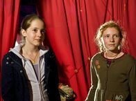 Tiere bis unters Dach – v.li.n.r.: Die Mädchen Greta (Enya Elstner) und Celine (Zora Achtnich) bewundern Toni in der Manege. Sie kommen, um ihm das Futter, das sie im Dorf für den Elefanten gesammelt haben, zu bringen.