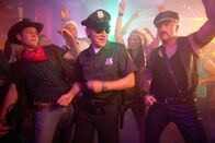 Wilsberg – Overbeck (Roland Jankowsky, M.) in seinem Element. Verkleidet als cooler US-Cop lässt er es bei der Mottoparty so richtig krachen.