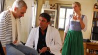 Der Bergdoktor – Der Bergdoktor Martin (Hans Sigl, M.) ist sich nicht sicher, was seinem alten Schulfreund Ferdinand (Hansa Czypionka, l.) wirklich fehlt. Dessen Frau Lena (Susanne Michel, r.) macht sich Sorgen.