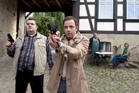 Alles Klara – In Sorge um Klara (Wolke Hegenbarth, rechts) stürmen Ollie (Christoph Hagen Dittmann, links) und Paul Kleinert (Felix Eitner, 2. von links) mit gezückten Pistolen in den Hof von Bauer Schiefer (Dietmar Huhn).