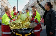 In aller Freundschaft – Während der Notarzt (Markus Neumann, 2.v.li.) und seine Kollegen (Jascha Rust (2.v.re.) und Sarah Zeising (li.), Komparse, 3.v.re.) den verletzten Fahrradfahrer (Tim Haberland, liegend) versorgen, filmt ein Gaffer (Albrecht Ganskopf) die ganze Zeit mit und steht den Rettungskräften ständig im Weg.