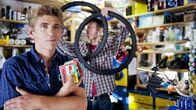 Löwenzahn – Fritz (Guido Hammesfahr, l.) ermittelt, wer einen Nutzen von den vielen platten Fahrrädern in der Umgebung hat. Fahrradhändler Wolle (Martin Schneider, r.) lauscht aufmerksam.