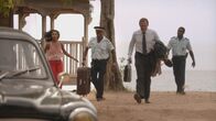Death in Paradise – Camille Bordey (Sara Martins, l.), Dwayne Myers (Danny John-Jules, 2.v.l.) und Fidel Best (Gary Carr, r.) bringen DI Richard Poole (Ben Miller, 2.v.r.) noch zum Auto, bevor er sich auf seine Reise macht. Das Team vermisst ihn jetzt schon.