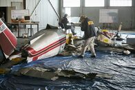 Mayday - Alarm im Cockpit – NTSB-Ermittler (gespielt von Schauspielern im Hintergrund) dokumentieren das Wrack der Piper Saratoga von John F. Kennedy Jr. und suchen nach Hinweisen, die erklären, warum das Flugzeug abgestürzt ist und Kennedy, seine Frau Carolyn Bessette-Kennedy und seine Schwägerin Lauren Bessette getötet hat.  