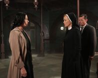 American Horror Story – Jahr 1964: Schwester Jude Martin (Jessica Lange, M.) war eigentlich überzeugt, dass es sich bei der Patientin tatsächlich um Anne Frank (Franka Potente, l.) handelt, bis plötzlich ihr Ehemann Jim (David Chisum, r.) auftaucht, der etwas anderes behauptet ...