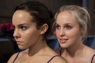 Dance Academy – Kat (Alicia Banit, re.) liebt es zu sticheln. Sie flüstert der neidischen Abigail (Dena Kaplan,li.) ins Ohr, wie gut Petra tanzt und wie begeistert Miss Raine von Petra ist.