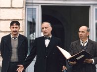 Die Kinder des Monsieur Mathieu – Der hartherzige Direktor Rachin (Francois Berléand, Mitte) und der ihm ergebene Chabert (Kad Merad, links) wollen mal wieder eine ihrer Bestrafungen durchführen. Der neue Lehrer Clément Mathieu (Gérard Jugnot) soll einen Schuldigen aus dem Klassenbuch auswählen, was ihm aber gar nicht behagt.