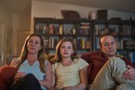 First Day - Ich bin Hannah – Hannahs Eltern Amanda (Jo Hunt, l.) und Steve (Mark Saturno, r.) versuchen Hannah (Evie MacDonald, M.) beim Fernsehgucken auf anderen Gedanken zu bringen.
