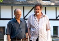 In aller Freundschaft – Pfarrer Peter Sänger (Gerd Baltus, rechts) führt Dietmar Bloch (Bernd Michael Lade) über das Kirchgelände. Obwohl Bloch sich der Chance, die ihm gegeben wird, bewusst ist, lehnt er das großzügige Jobangebot misstrauisch ab. Als er den Pfarrer eiskalt stehenlassen will, passiert etwas Unerwartetes.