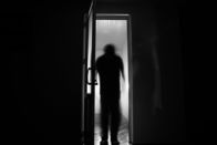 Ghost Hunters – Silhouette einer unbekannten Schattenfigur an einer Tür durch eine geschlossene Glastür.