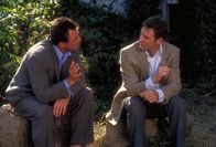 In & Out – Howards (Kevin Kline, r.) Leben wird auf den Kopf gestellt, als ein ehemaliger Schüler ihn als schwul outet. Reporter aus dem ganzen Land stürzen sich auf die Story. Doch nur Peter Malloy (Tom Selleck, l.) scheint etwas daran zu liegen, Howards Seite zu hören.
