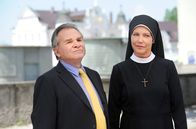 Um Himmels Willen – MDR Fernsehen UM HIMMELS WILLEN XIII. STAFFEL FOLGE 158, "Feuer unterm Dach" Uhr. Wolfgang Wöller (Fritz Wepper, l.) ist sprachlos - Schwester Hanna (Janina Hartwig, r.) hat eine medienwirksame Hausbesetzung angezettelt, um die Schließung des Seniorentreffs zu verhindern.