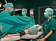 In aller Freundschaft – Bei der Operation von Marie (Henriette Zimmeck, liegend) stellen Dr. Roland Heilmann (Thomas Rühmann, links) und Dr. Elena Eichhorn (Cheryl Shepard, 2. von links) eine Nierenverletzung fest. Als klar ist, was der Grund für Maries Zustand war, sind Dr. Kathrin Globisch (Andrea Kathrin Loewig) und die anderen erleichtert.