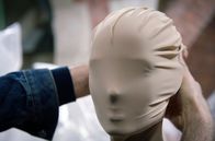Martin Margiela - Mythos der Mode – Martin Margiela legt eine Maske an einem Modell an. Der 1957 geborene belgische Modedesigner inspiriert bis heute viele seiner jüngeren Kolleginnen und Kollegen, ohne sein Gesicht in der Öffentlichkeit gezeigt zu haben.