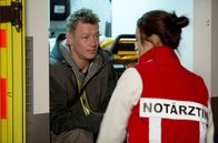 Die Notärztin – Netto (Vincent Krüger, l.) sitzt im RTW und bittet Nina (Sabrina Amali, r.) Paul (Paul Zichner) nicht zu kündigen.