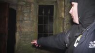 Unheimliche Videos - Wahrheit oder Fake? – Der Mann zeigt auf die dunkle Tür.
