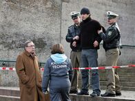 Polizeiruf 110 – Taxiunternehmer Georg Sendler (Tobias Oertel, oben Mitte) wird an der Absperrung von Beamten festgehalten. Schmücke (Jaecki Schwarz, links) kommt dazu.