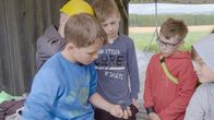 SommerCamp - Back To the Roots – Gespannt schauen die anderen Jungs Alvin beim Devilstickbauen über die Schulter.