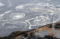 Japans Erdbebenkatastrophe – Ein Tsunami mit aufgerollten Wellen nähert sich einer Küste in Iwaki, Präfektur Fukushima, ein Bild, das am Freitag, den 11. März 2011, vom Helikopter der Yomiuri aufgenommen wurde. Das schwere Erdbeben im Nordosten Japans löste am 11. März 2011 einen Tsunami und ein Feuer aus, das die Pazifikküste des japanischen Archipels verwüstete. Bei dem stärksten Beben kamen Hunderte von Menschen ums Leben.