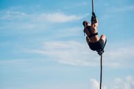 Exatlon Germany – Rückansicht einer Sportlerin, die an einem körperlich anstrengenden Hindernislauf teilnimmt, während sie an einem Seil hochklettert und eines der Hindernisse überwindet.