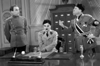 Der große Diktator – Als der Diktator Napaloni (Jack Oakie, re.) zu Besuch ist, versucht Dr. Garbitsch (Henry Daniell, li.) mit allerlei Strategien, den Anschein einer Übermacht Hynkels (Charles Chaplin, Mi.) zu erwecken. Doch Napaloni lässt Hynkel trotzdem ganz klein wirken.