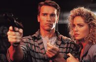 Total Recall – Der Bauarbeiter Douglas Quaid (Arnold Schwarzenegger, l.) führt eigentlich ein zufriedenes Leben mit seiner attraktiven Frau Lori (Sharon Stone, r.), doch immer wieder träumt er von einem anderen Leben und einer fremden Frau. Was hat das zu bedeuten?