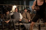 Babylon Berlin – Kommissar Rath (Volker Bruch, re.) bei Gangsterboss Weintraub (Ronald Zehrfeld, Mitte) und dessen Handlanger Max (Sebastian Urzendowsky, li.) am Boxring.