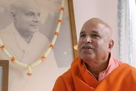 Yoga - Der Atem Indiens – Swami Yoga Swarupananda im Ashram der Devine Light Society in der Stadt Rishikesh/Indien vor einem Bild von Swami Sirandanda