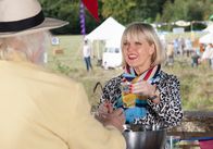 Agatha Raisin – Agatha Raisin (Ashley Jensen) schenkt auf dem Carsely-Fest Getränke aus und hat dabei große Freude.