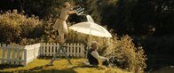 Nur ein Tag – Kleine Fliegenweisheit: Auf Sonne folgt Regen, folgt Sonne. Die fröhliche Eintagsfliege (Karoline Schuch) auf einer Leiter stehend, gießt mit einer Gießkanne auf Wildschwein (Aljoscha Stadelmann), der unter einem Schirm sitzt.