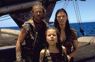 Waterworld – Helen (Jeanne Tripplehorn, r.) befreit den Mariner (Kevin Costner, l.), um gemeinsam mit ihm und ihrer Ziehtochter Enola (Tina Majorino, M.) ins Dryland zu fliehen. Denn auf Enolas Rücken befindet sich eine Tätowierung, die den Weg dorthin weist ...