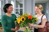 Die Rosenheim-Cops – Noch glaubt Controllerin Ortmann (Diana Staehly, r.), dass der Blumenstrauß für sie bestimmt ist. Sekretärin Stockl (Marisa Burger, l.) freut sich mit ihr.