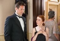Agatha Raisin – Karen Sheppard (Rosie Day) informiert sich am Stand der Detektei, was Anzeichen für einen Seitensprung des Partners sein können, während ihr Ehemann Luke Sheppard (James Anderson) daneben steht.