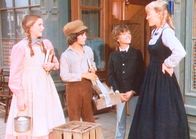 Unsere kleine Farm – Nellie (Alison Arngrim, r.) und Willie (Jonathan Gilbert, 2.v.r.) prahlen mit ihren Schuluniformen, doch Laura (Melissa Gilbert, l.) und Albert (Matthew Laborteaux, 2.v.l.) lassen sich davon nicht beeindrucken.