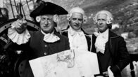 Die Schatzinsel – Die Hispaniola ist vor der Schatzinsel angelangt. Kapitän Smollet (Jacques Monod, l.) erläutert Trelawney (Jacques Dacquemine, m.) und Dr. Levesey (Georges Riquier, r.) anhand der alten Karte des Seeräubers Flint die Einfahrt in die Ankerbucht.