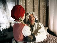 Rotkäppchen – Der böse Wolf (Edgar Selge) hat sich als Rotkäppchens Großmutter verkleidet und versucht, Rorkäppchen (Amona Aßmann) zu verschlingen.