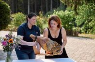 Lecker aufs Land – Judith Wohlfahrt (re.) und Larissa Schmidt bereiten zur Begrüßung der Landfrauen einen zwei Jahre alten luftgetrockneten Schinken vor.