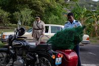 Death in Paradise – Officer Marlon Pryce (Tahj Miles, r.) bringt unter dem skeptischen Blick des Polizeichefs (Don Warrington, l.) einen Tannenbaum zur Polizeistation.