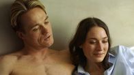 Hidden Agenda – Emily (Josefin Asplund) kuschelt mit ihrem Freund und Kollegen Henrik (Christian Hillborg) auf dem Bett. Langsam öffnet Emily sich ihm, was ihre Beziehung auf die nächste Ebene bringen könnte.