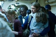 World War Z – Als unentbehrlicher Helfer im Kampf gegen die Zombie-Seuche kann Gerry (Brad Pitt, r.) seine Frau Karen (Mireille Enos, l.) und die Töchter (auf seinem Arm Sterling Jerins als Constance) zunächst auf einem Flugzeugträger auf dem offenen Meer in Sicherheit bringen. Der stellvertretende Generalsekretär der UN, Thierry Umutoni (Fana Mokema, M.) hat einen wichtigen Auftrag für Gerry.